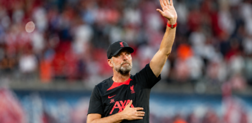 Jürgen Klopp raises a hand to acknowledge supporters inside a football stadium