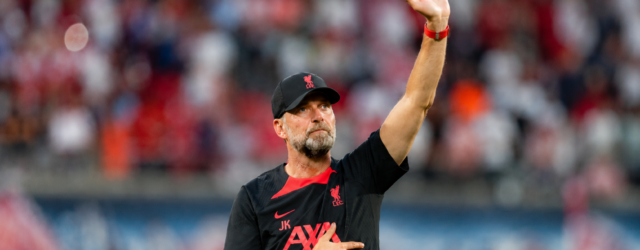 Jürgen Klopp raises a hand to acknowledge supporters inside a football stadium