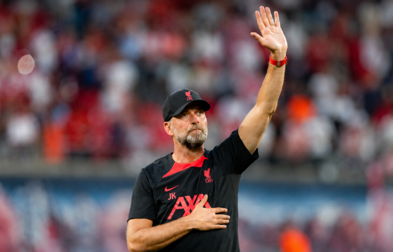 Jürgen Klopp raises a hand to acknowledge supporters inside a football stadium