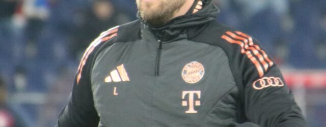 Harry Kane wearing a black Bayern Munich training jacket before a match, with the club badge visible on his chest.